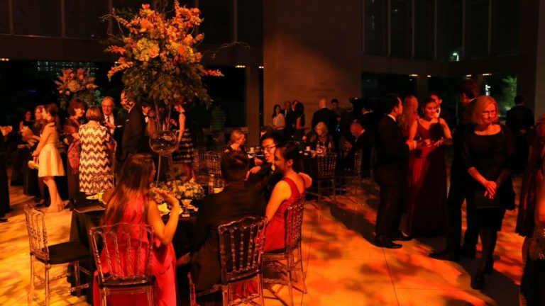 After party at the Meyerson - patrons mingling and chatting with very dramatic dark gold and red lighting