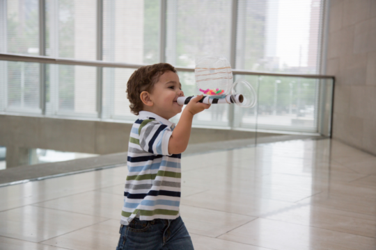 Young child plays with a homemade instrument