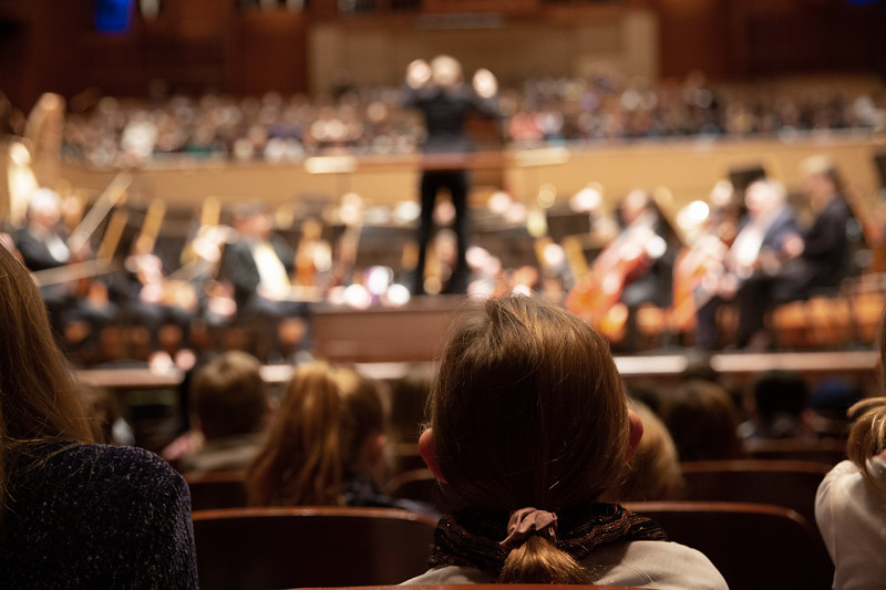 Students watching the stage, photographed from behind.