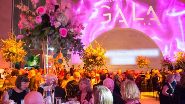 seated gala dinner for the DSO with dramatic pink and gold lighting and patrons seated at round tables
