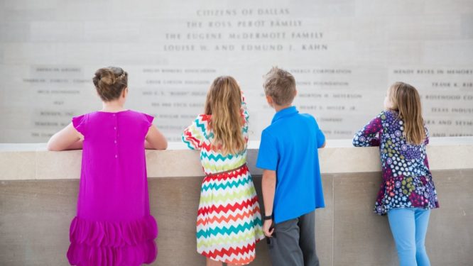 Three girls and a boy looking over the balcony in the Meyerson lobby