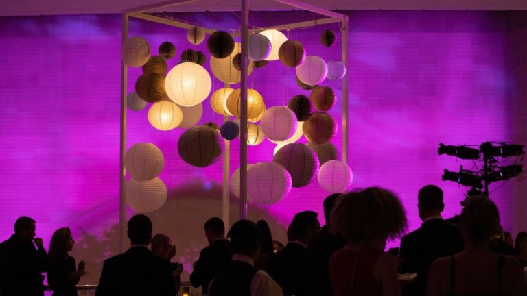 Loge lounge con accesorios modernos y una dramática iluminación rosa y púrpura.