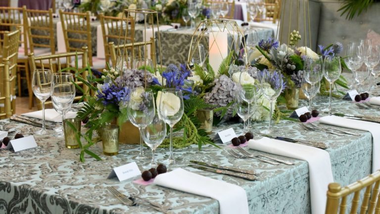 Paisaje de mesa inspirado en la primavera en el Meyerson - tonos de flores verdes, lilas y azules para los centros de mesa, acentuado con candelabros y sillas doradas
