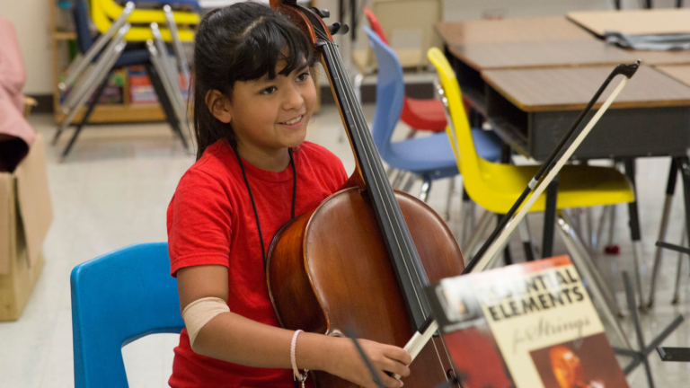 Jóvenes músicos estudiantes aprendiendo a tocar el violonchelo