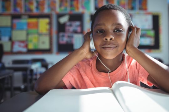 little boy wearing headphones and looking at computer