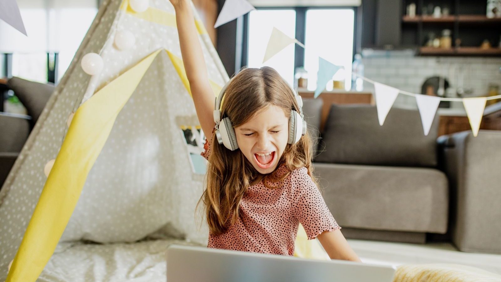 una niña pequeña jugando un juego en línea y ganando en su casa