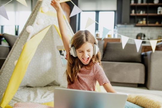 una niña pequeña jugando un juego en línea y ganando en su casa