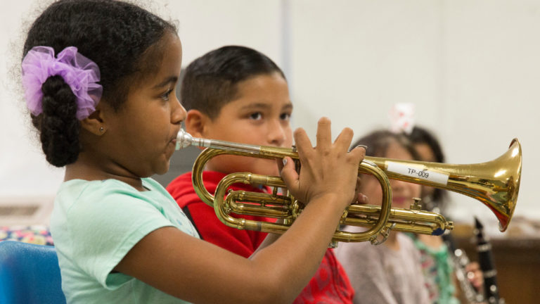 Las niñas tocan la trompeta junto a otros niños
