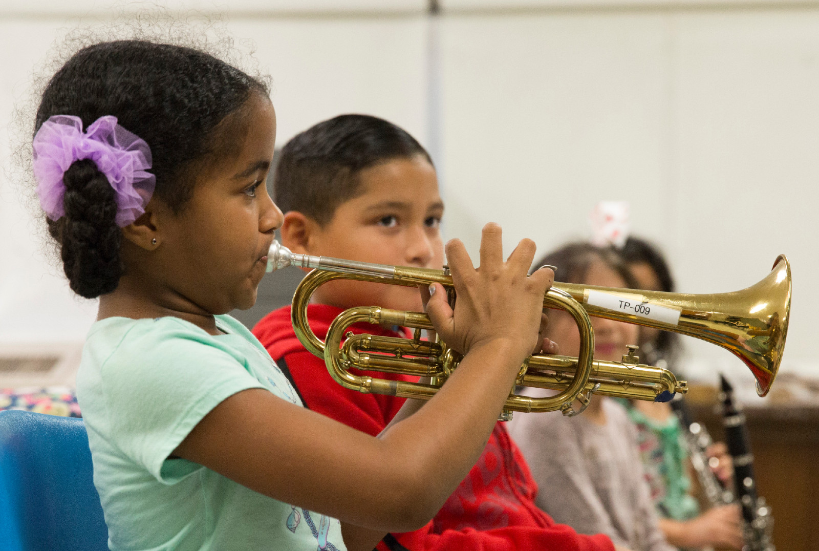 Girls plays trumpet next to other children