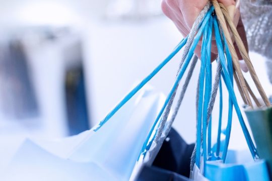 La mujer que lleva muchas bolsas de compras azules