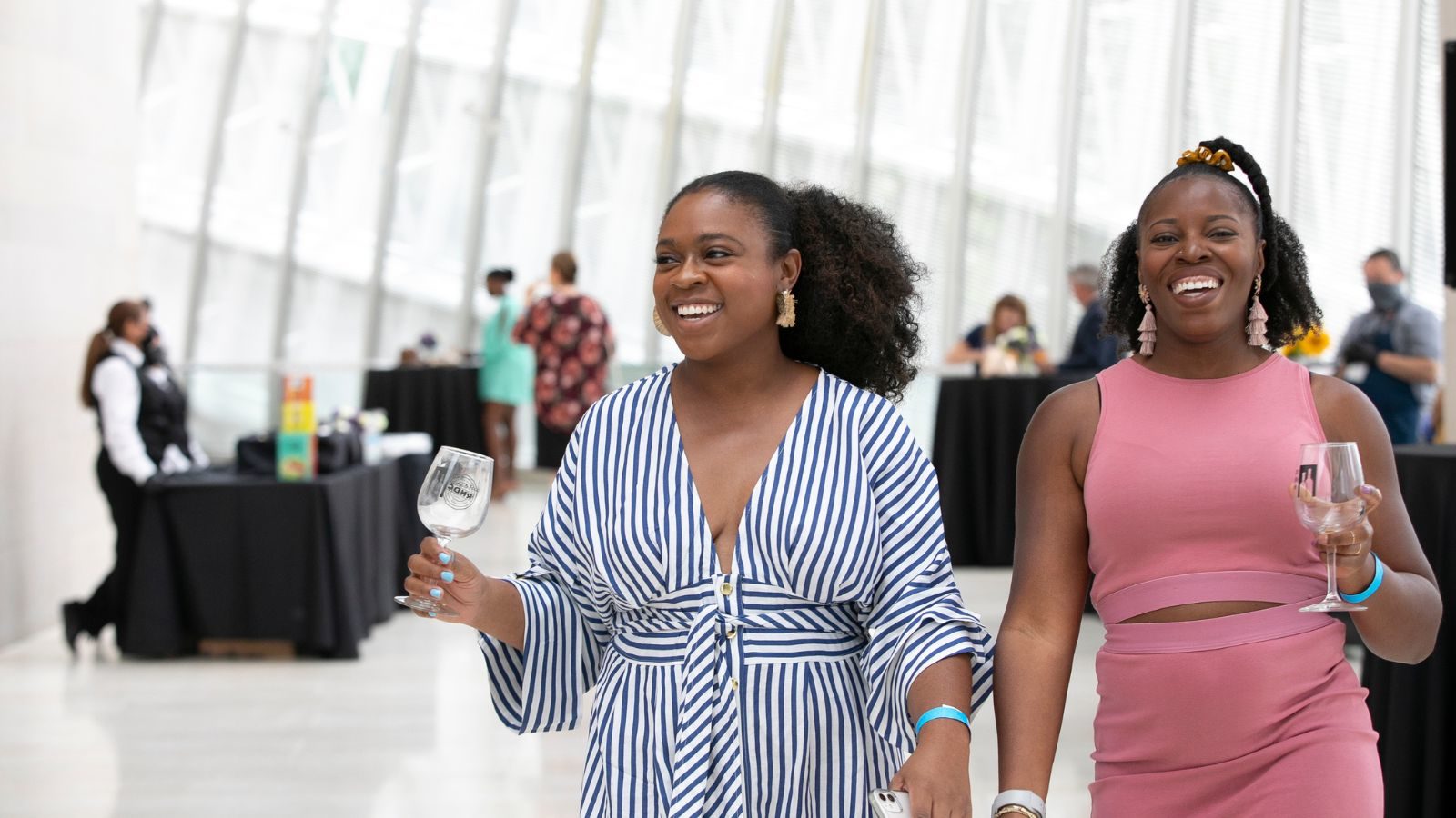 Grand Tasting - Two people walking with wine glasses in their hand.