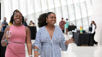 Grand Tasting - Two people walking with wine glasses in their hand.